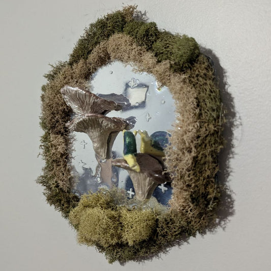 A moss-bordered hexagonal mirror with fake shimmery mushrooms growing out of the center